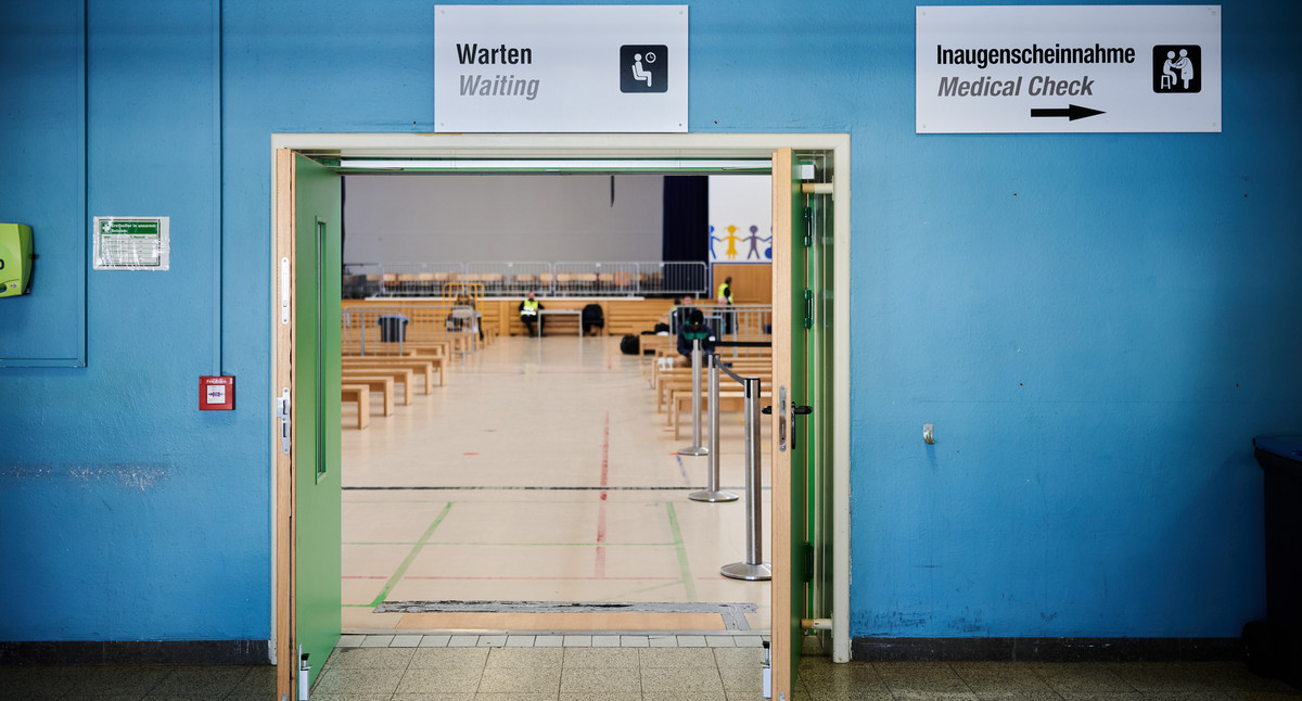 Das Bild zeigt den Blick durch eine geöffnete Tür in einen Saal mit Bankreihen.