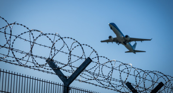 Fliegendes Flugzeug über Drahtzaun