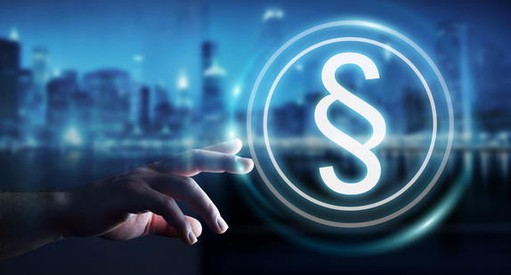 Eine Hand greift nach einem digitalen Paragrafen