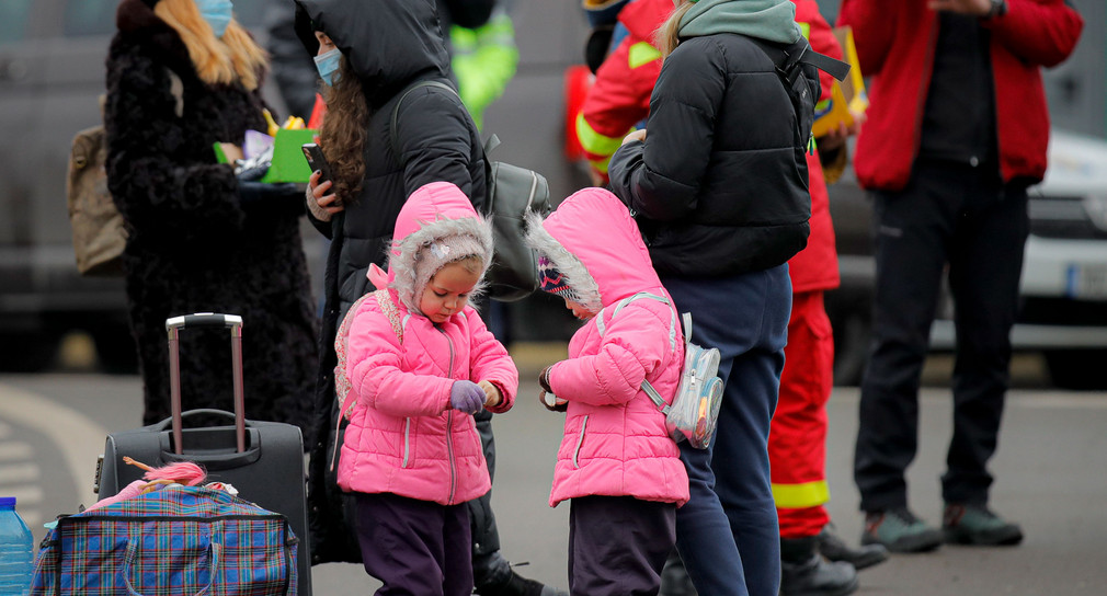 Ukrainische Kinder öffnen an der rumänisch-ukrainischen Grenze Süßigkeiten, die sie von Freiwilligen erhalten haben, nachdem sie vor dem Konflikt in der benachbarten Ukraine geflohen sind.