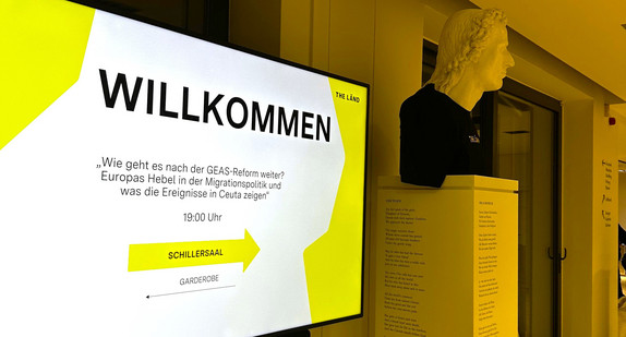 Willkommensschild mit der Aufschrift "Wie geht es nach der GEAS-Reform weiter? Europas Hebel in der Migrationspolitik und was die Ereignisse in Ceuta zeigen"