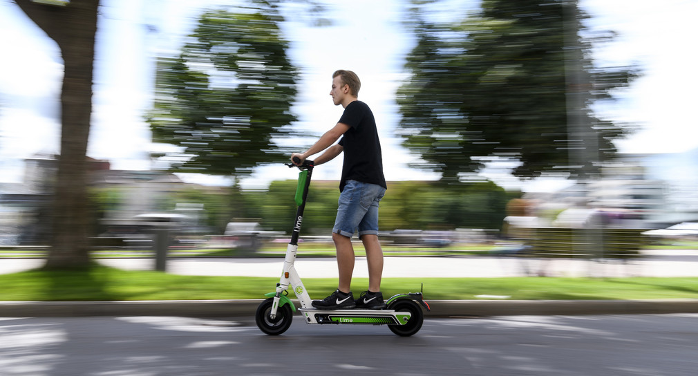 Ein Mann fährt auf einem E-Tretroller (Bild: © Edith Geuppert/dpa)