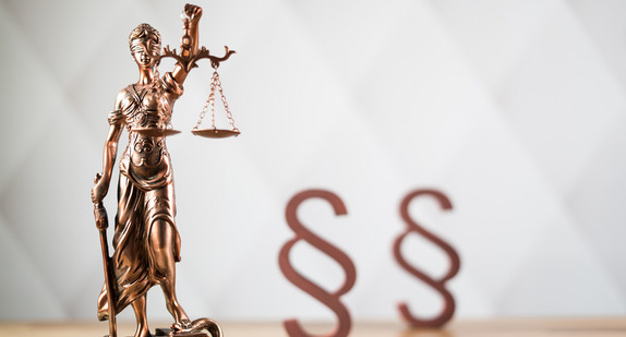 Justitia links neben zwei Paragraphen